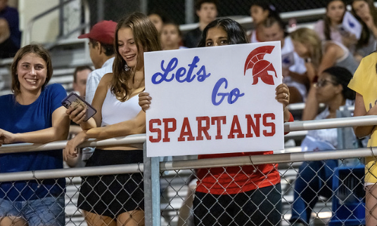 A Spartan fan holds a homemade sign and cheers on the team.